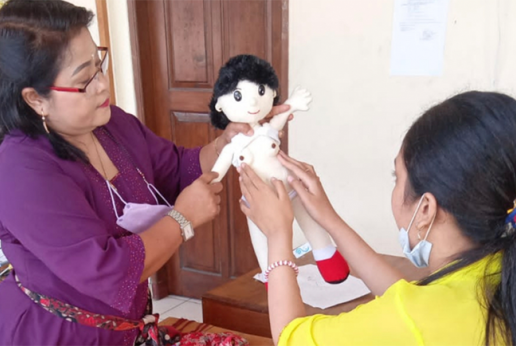 A woman is holding a female anatomy doll while showing it to a girl