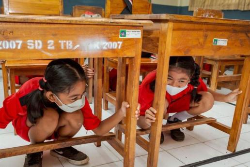 Two schoolgirls are hiding below school desks