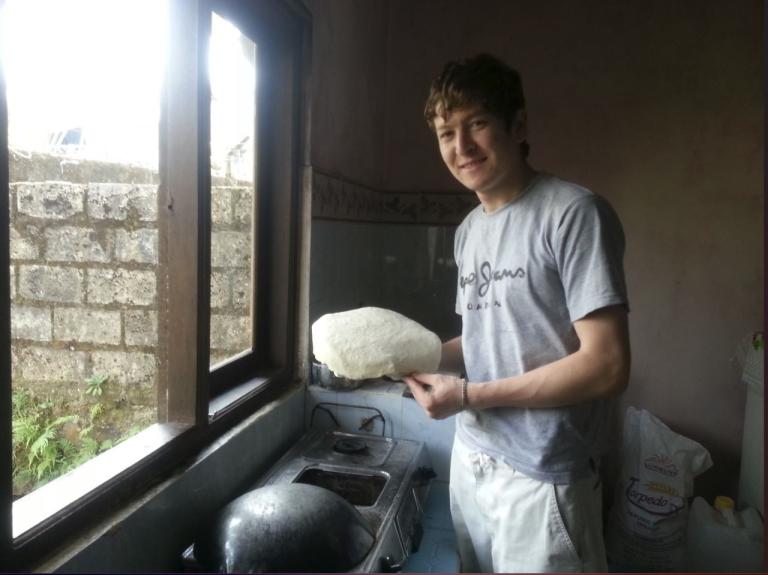 A man from Afghanistan is posing in a kitchen, holding a bread he made