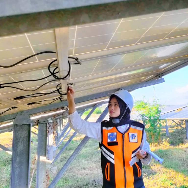 A uniformed woman is standing under a solar panel installation