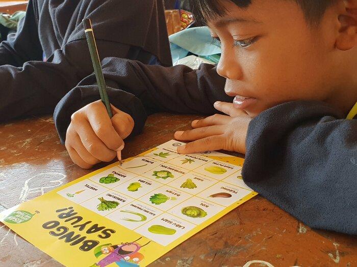 A boy is playing a vegetable bingo